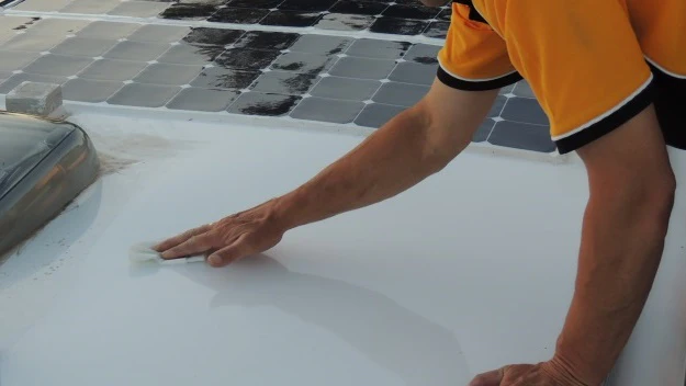 Person cleaning the roof of an RV with isopropyl alcohol cleaning solution